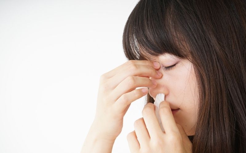 Woman with nosebleed pinching her nose
